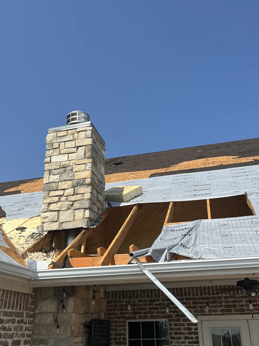 Tear-off in progress around the stone chimney with the decking and framing open