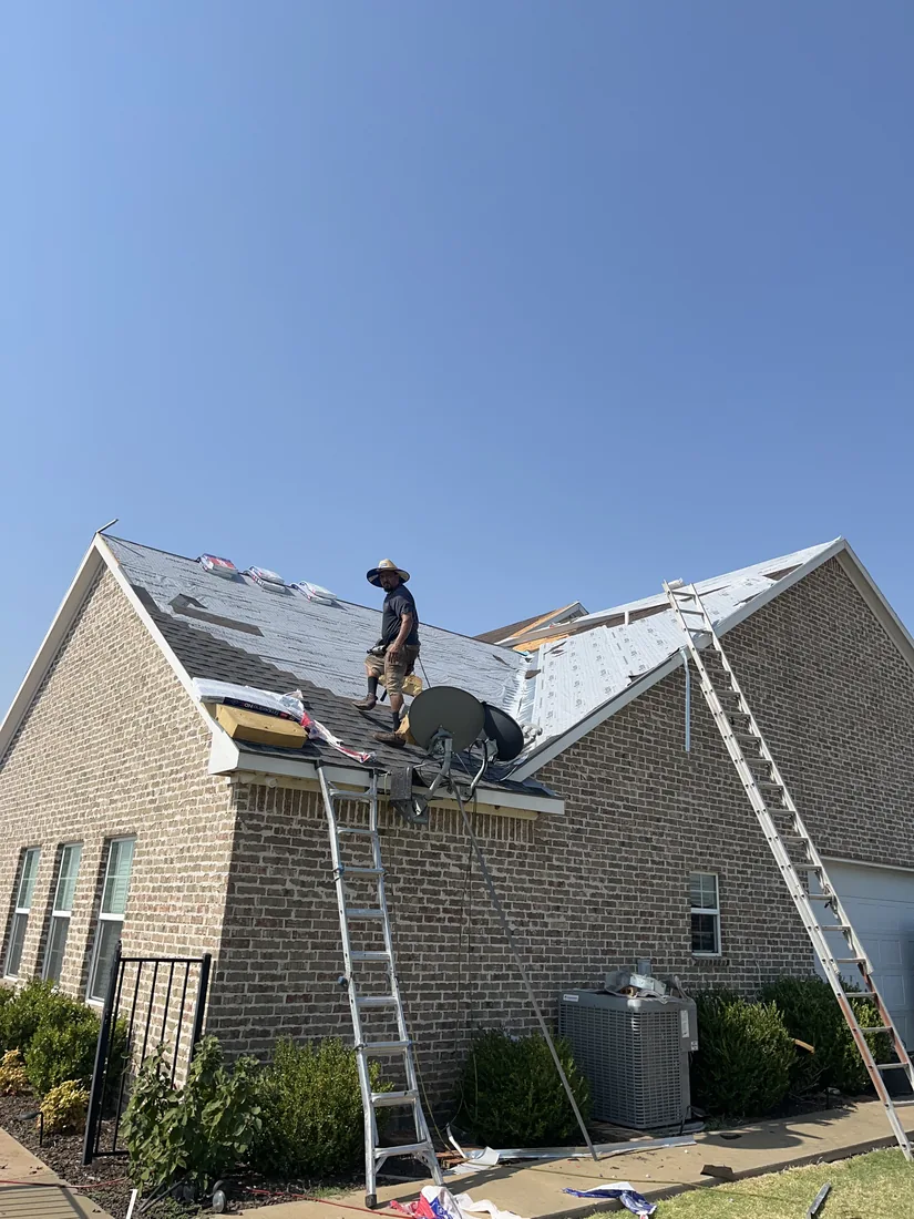 A Lankford crew member working the slope with synthetic underlayment down and ladders set